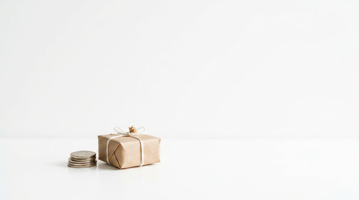 A small kraft-paper gift box with a white string bow next to a stack of coins